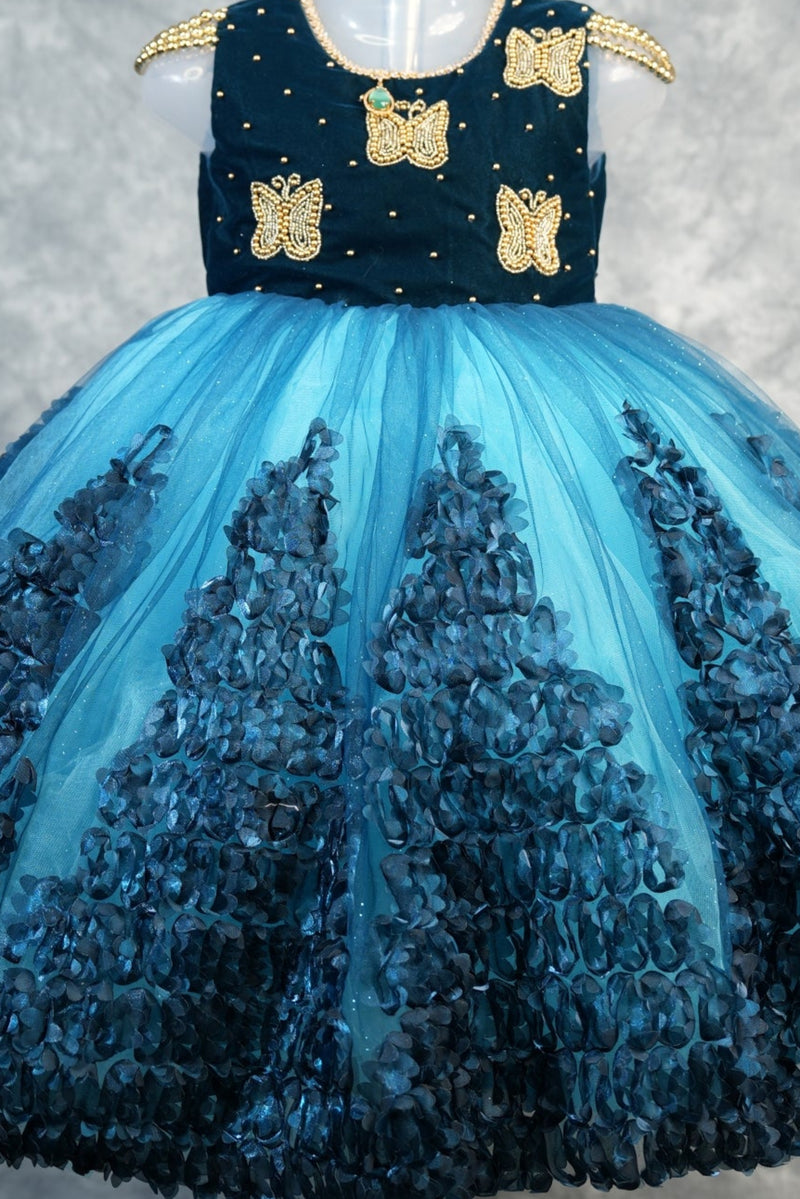 Deep Teal with Peacock Blue Baby Girls Frock Rich teal velvet bodice with gold butterfly appliqués & pearl dots, flowy peacock blue tulle skirt with 3D petal clusters.Birthday party wear!