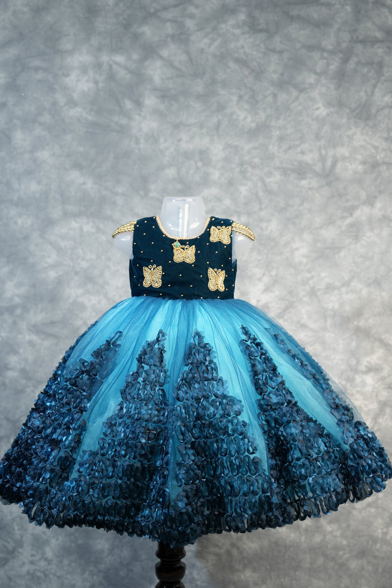 Deep Teal with Peacock Blue Baby Girls Frock Rich teal velvet bodice with gold butterfly appliqués & pearl dots, flowy peacock blue tulle skirt with 3D petal clusters.Birthday party wear!
