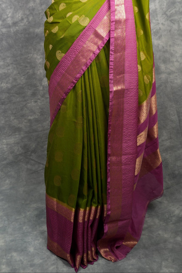 Green and pink saree on a mannequin against a gray background
