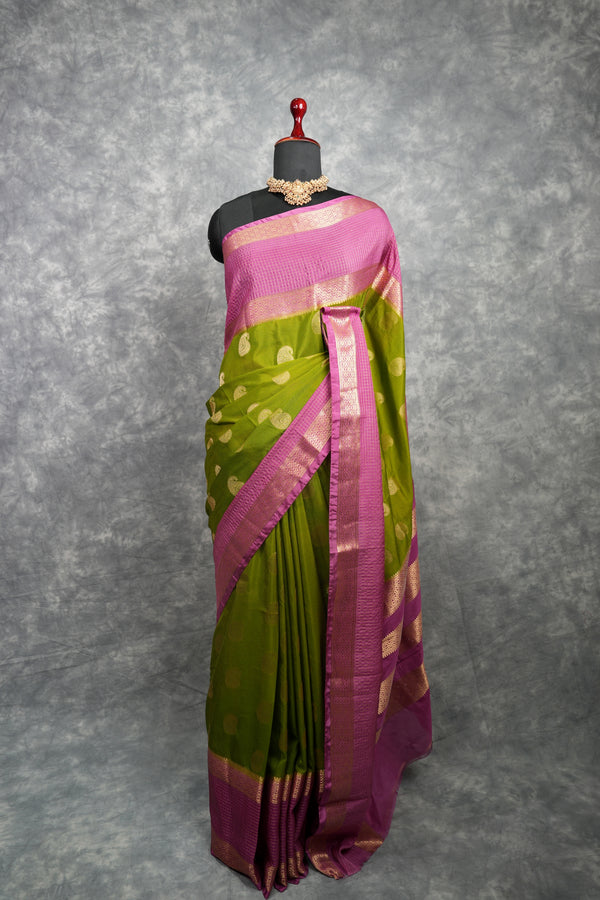 Green and pink saree on a mannequin against a gray background