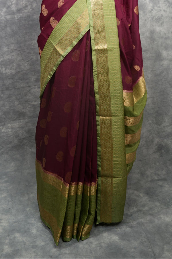 Saree with maroon and green pattern on a mannequin against a gray background