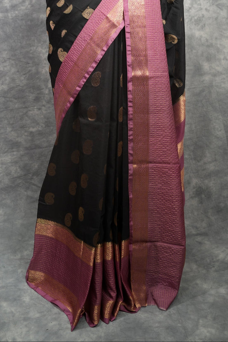 Black saree with pink border on a mannequin against a gray background