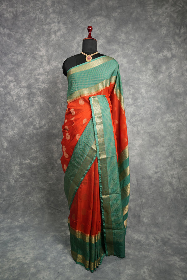 Red and green saree with gold border on a mannequin against a gray background
