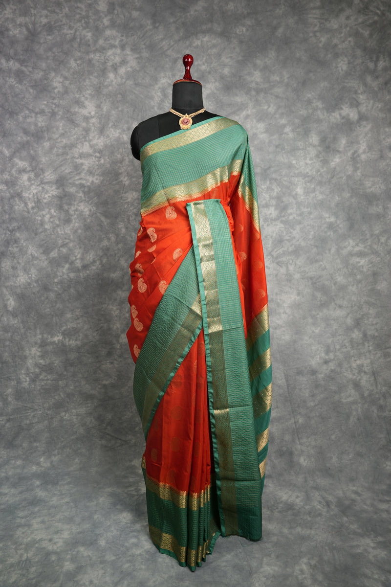 Red and green saree with gold border on a mannequin against a gray background