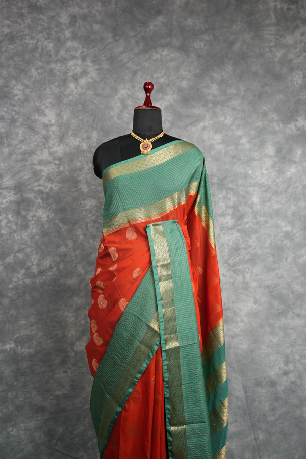 Red and green saree with gold border on a mannequin against a gray background