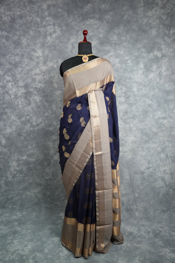 Navy blue saree with gold patterns on a mannequin against a gray background