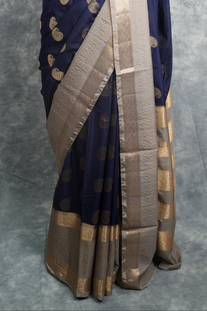 Navy blue saree with gold patterns on a mannequin against a gray background