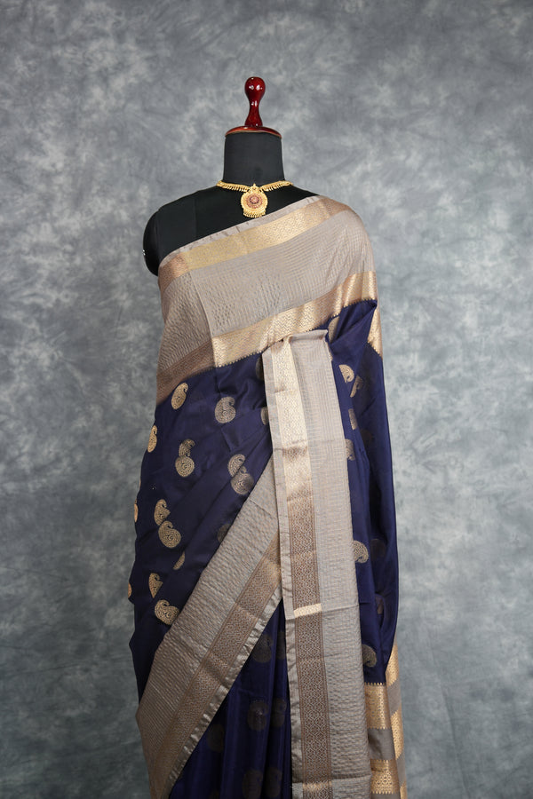 Navy blue and beige saree with gold patterns on a mannequin against a gray background