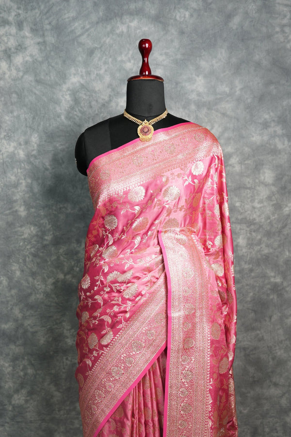 Pink saree with white floral patterns on a mannequin against a gray background