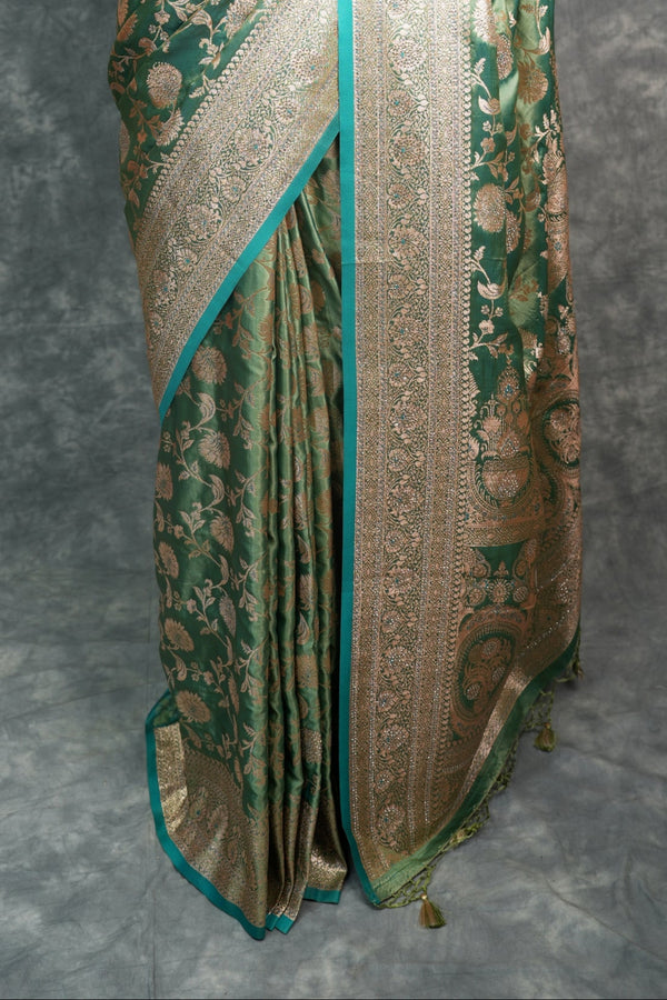 Saree with gold and green patterns on a mannequin against a gray background