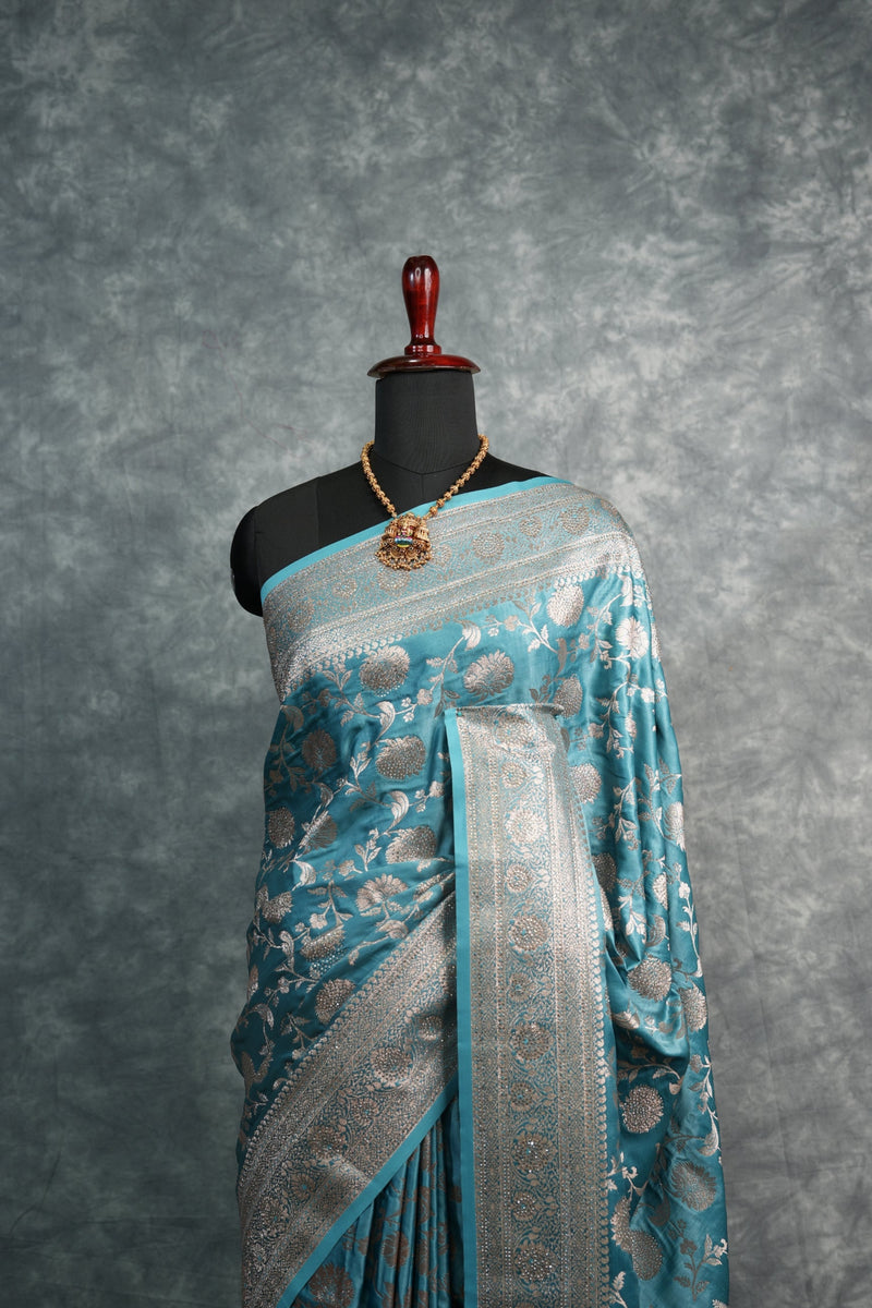 Traditional blue and silver embroidered garment on a gray background