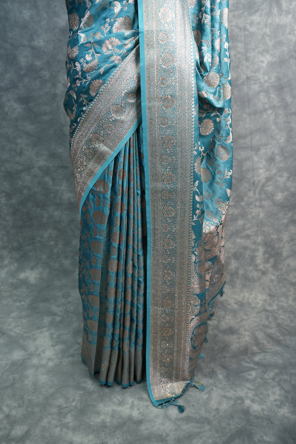 Folded blue and silver saree on a gray background