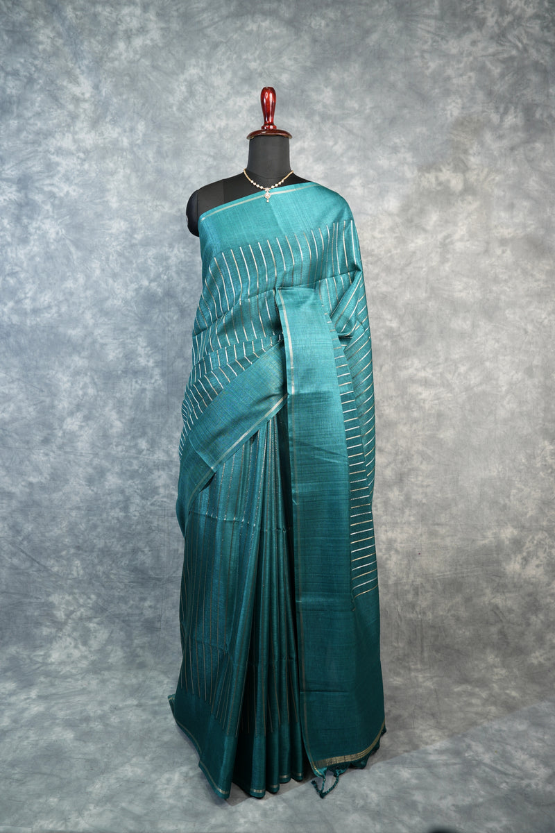 Teal saree with white patterns on a mannequin against a gray background