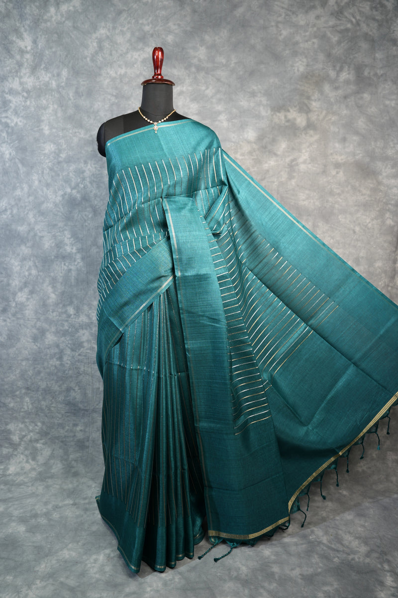 Teal saree with white patterns on a mannequin against a gray background