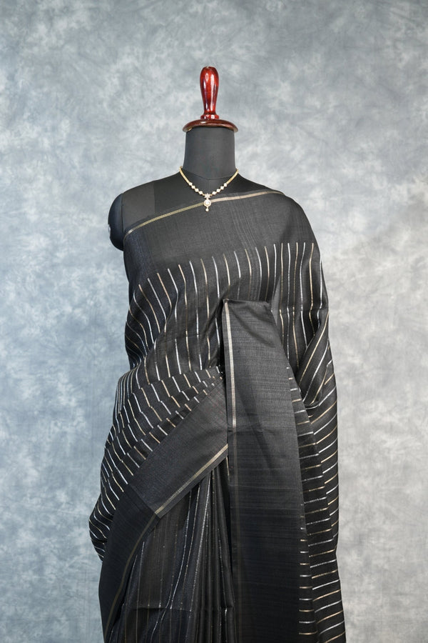 Black saree with white patterns on a mannequin against a gray background