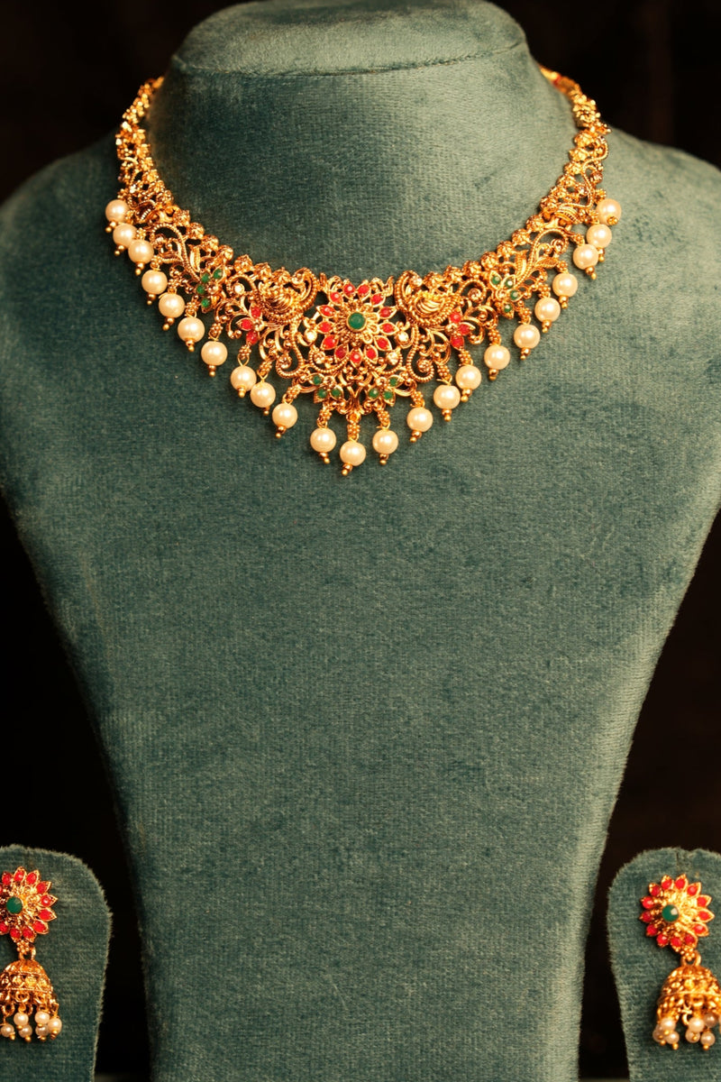 Jewelry set with necklace and earrings on a green mannequin bust against a black background