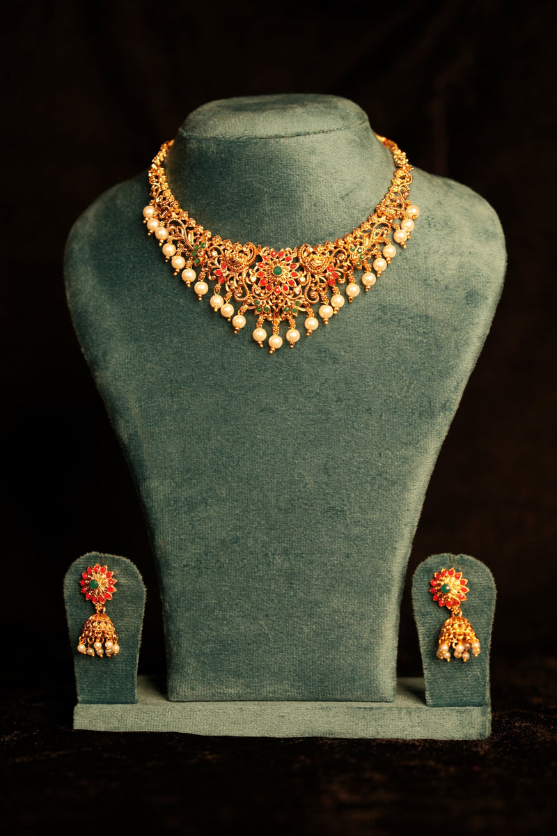 Jewelry set with necklace and earrings on a green mannequin bust against a black background
