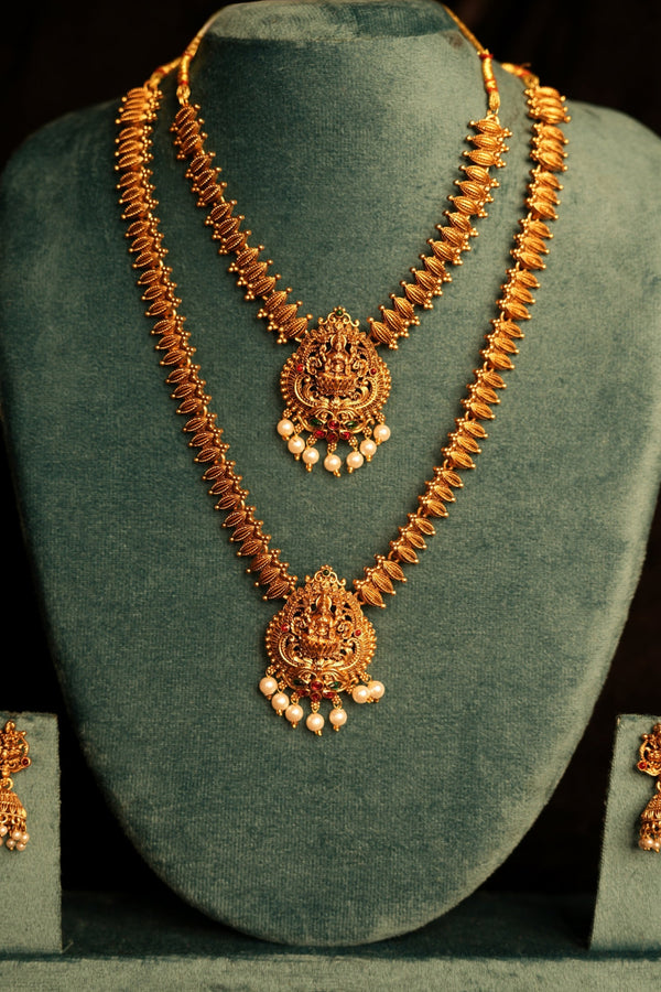 Jewelry set with necklace and earrings on a green stand against a black background