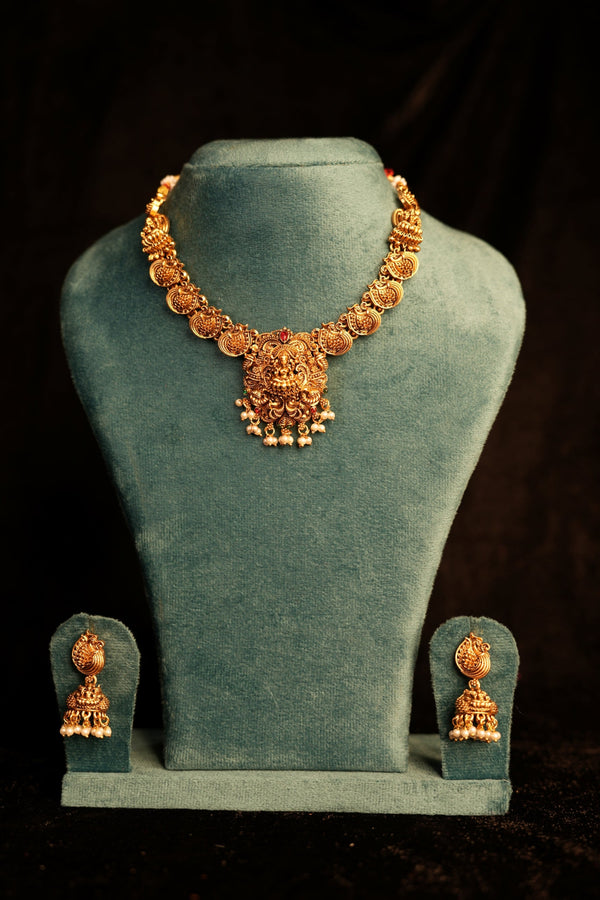 Gold jewelry set on a green velvet stand against a dark background