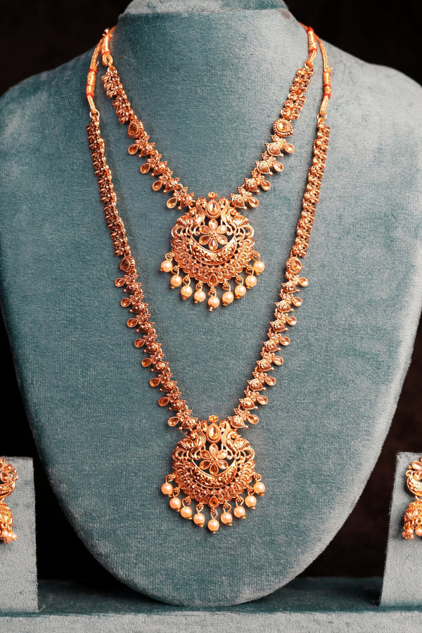 Rose gold necklace and earrings on a gray stand against a black background