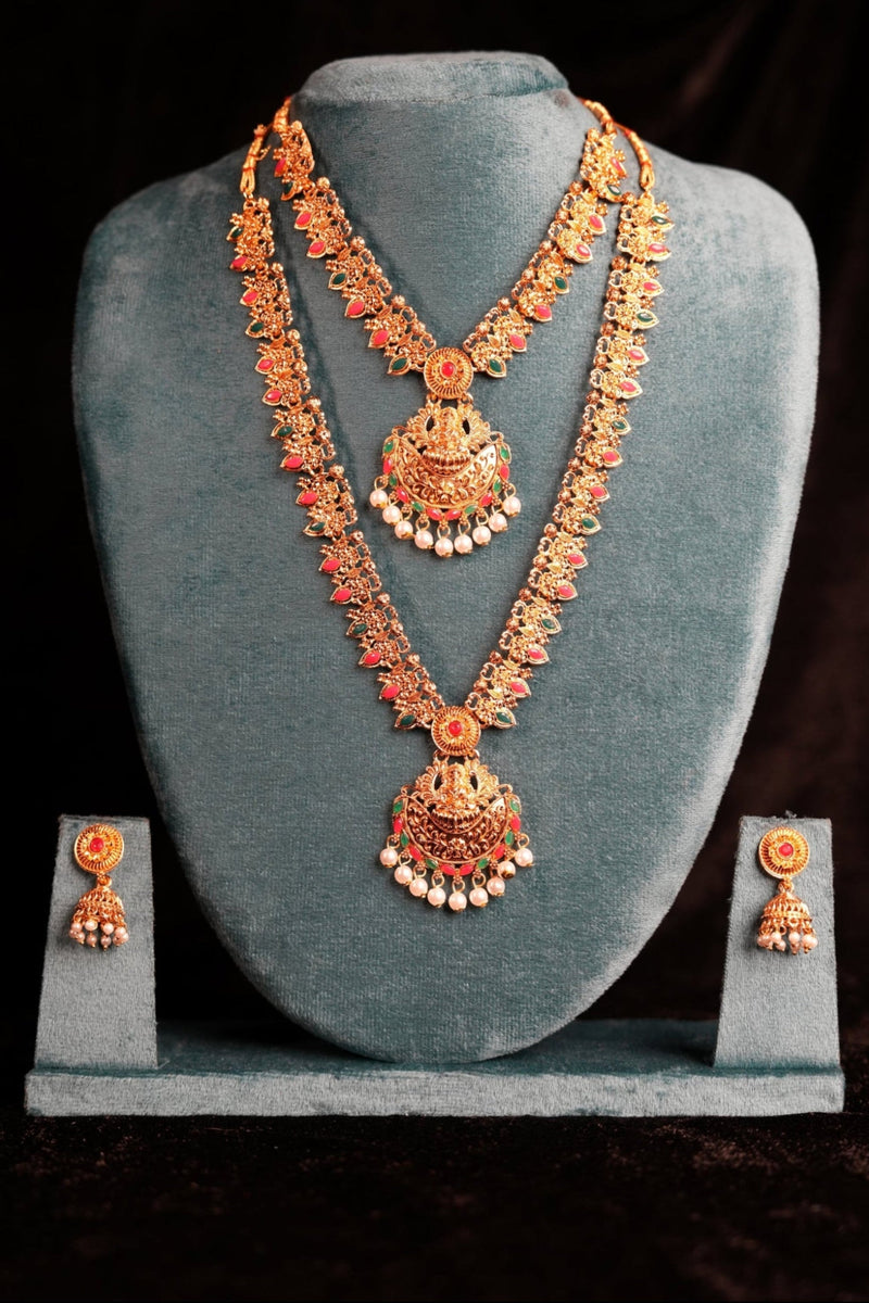 Gold jewelry set with necklace and earrings on a gray stand against a dark background