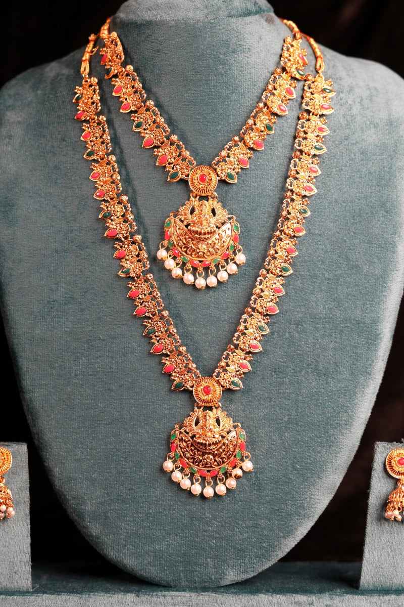 Gold jewelry set with necklace and earrings on a gray stand against a dark background