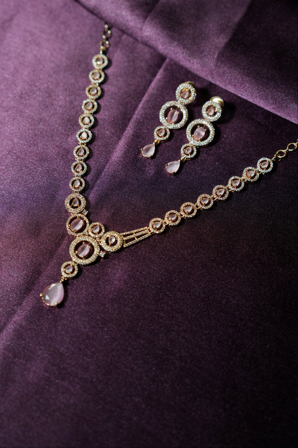 Gold necklace with teardrop-shaped pendants on a purple fabric background