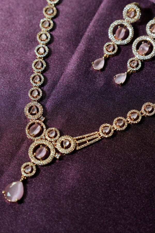 Gold jewelry set with circular designs on a purple fabric background
