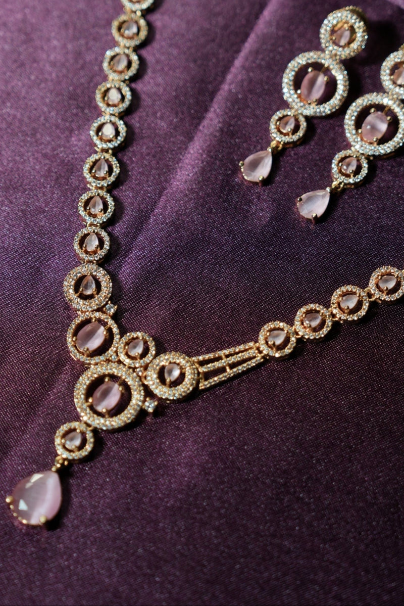 Gold jewelry set with circular designs on a purple fabric background