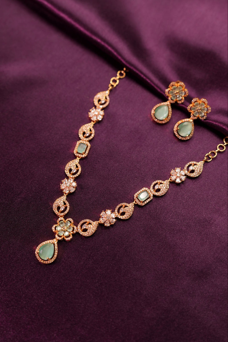 Gold necklace with green gemstones on a purple fabric background