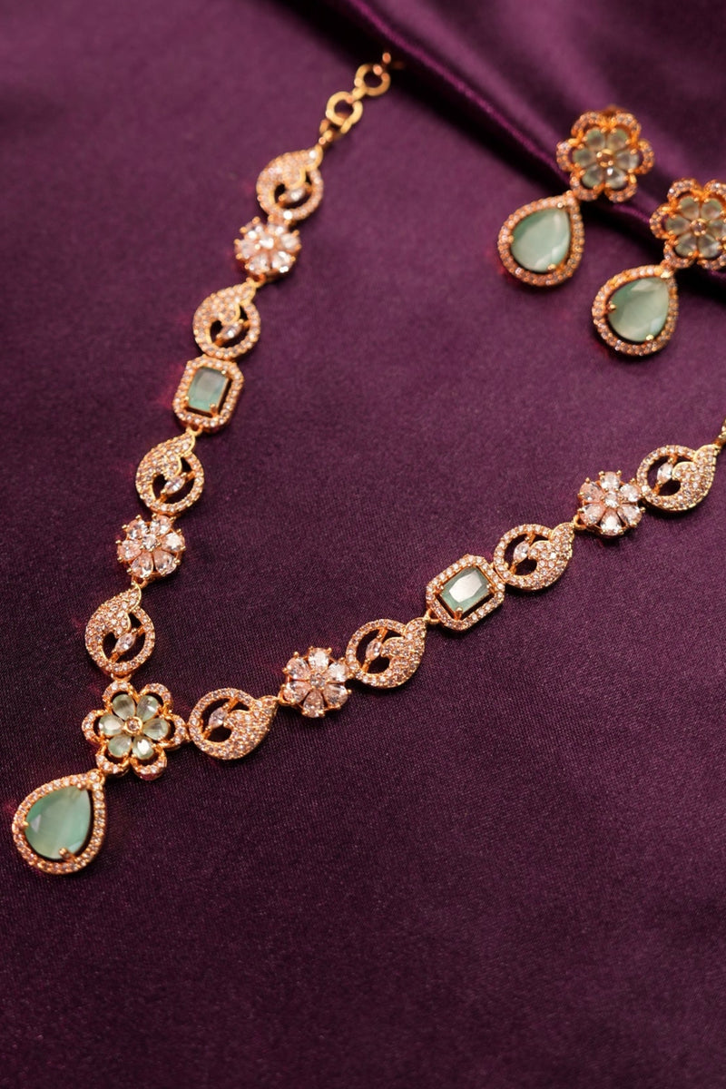 Gold necklace with green gemstones on a purple fabric background