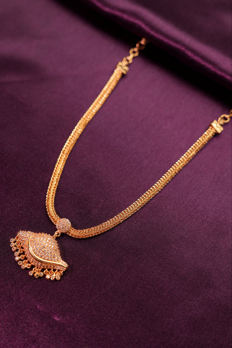 Gold necklace with decorative pendant on a purple fabric background