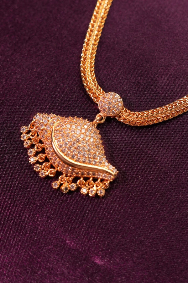 Gold necklace with decorative pendant on a purple fabric background