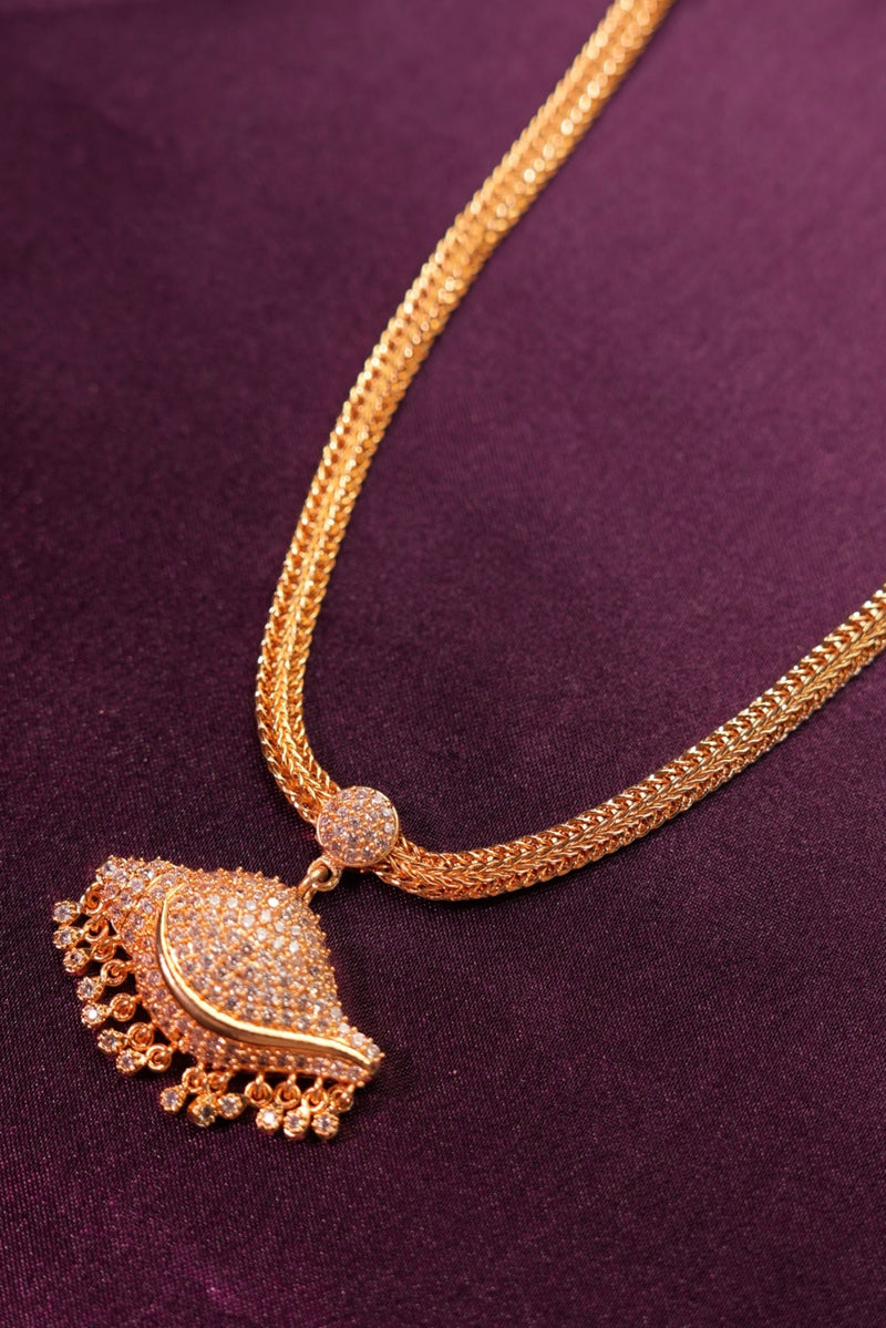 Gold necklace with decorative pendant on a purple fabric background