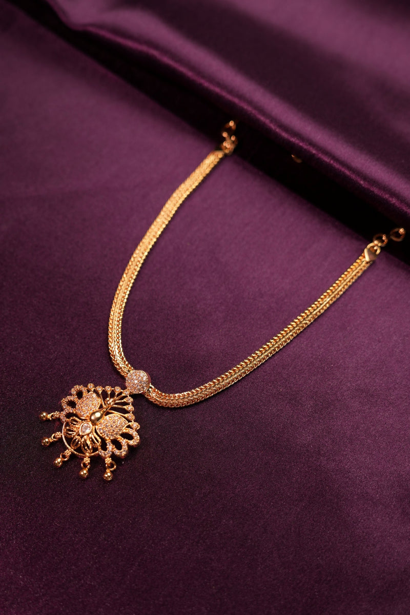 Gold necklace with decorative clasp on a purple fabric background