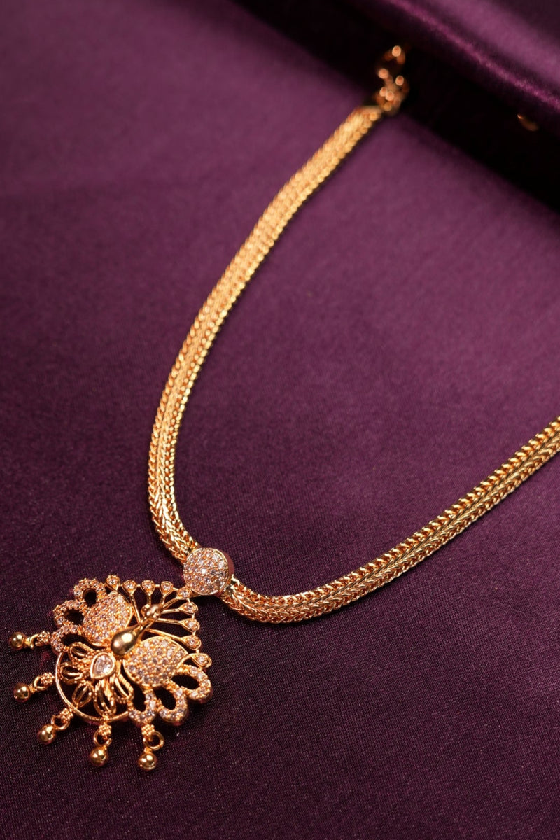 Gold necklace with decorative clasp on a purple fabric background