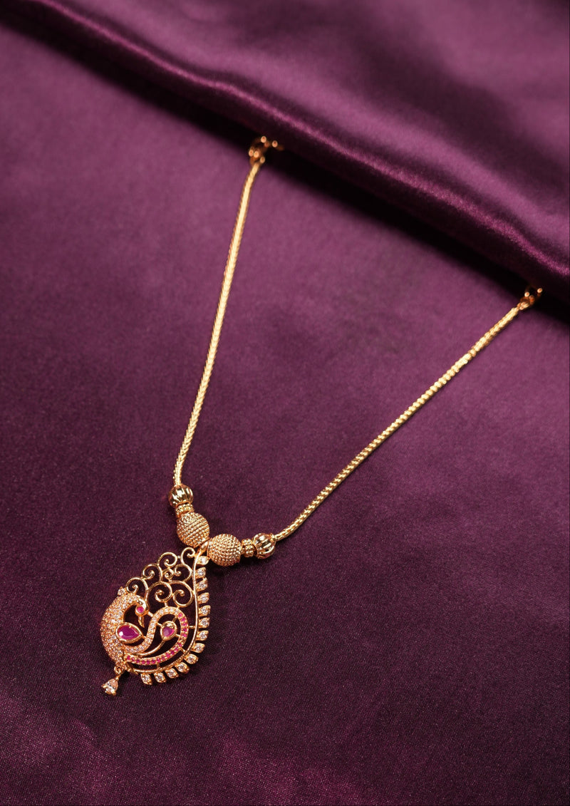 Gold necklace with a pendant on a purple fabric background