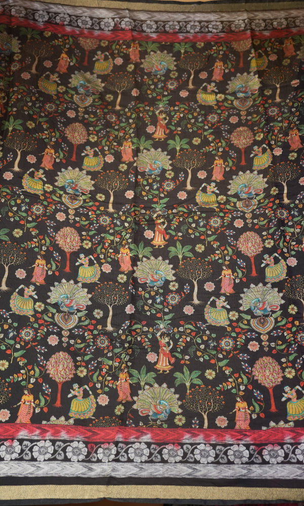 A close-up of a dark patterned textile or fabric featuring a folk-art style print of dancing figures, floral motifs, and stylized trees in red, green, yellow, and white, with decorative border bands at the top and bottom.