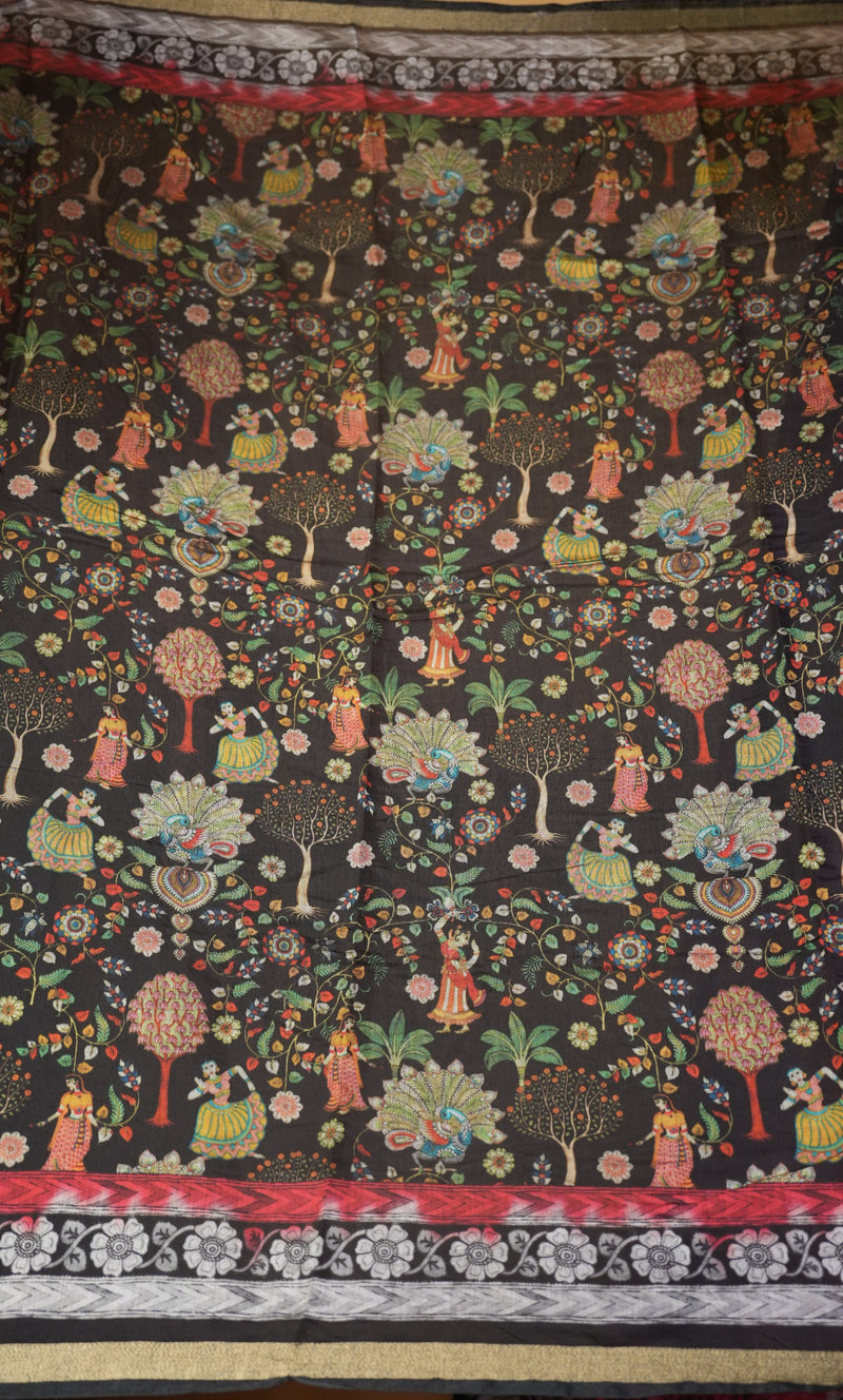 A close-up of a dark patterned textile or fabric featuring a folk-art style print of dancing figures, floral motifs, and stylized trees in red, green, yellow, and white, with decorative border bands at the top and bottom.
