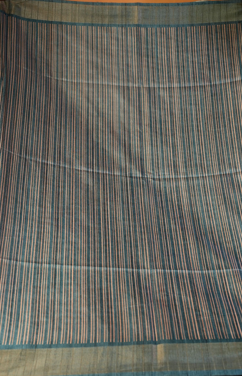 A close-up of a striped fabric, likely a saree or scarf, featuring vertical stripes in blue, beige, and brown on a light olive-green base.