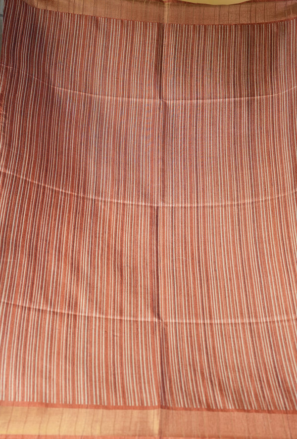 A close-up of a striped fabric, likely a sari, featuring vertical stripes in terracotta red, orange, and beige with a solid orange border.