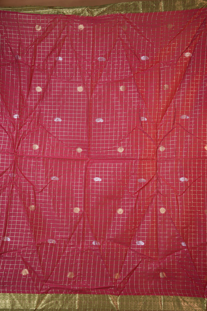 A red saree or fabric panel with a white grid pattern and small gold and white motifs, laid flat with a gold border visible on the sides.