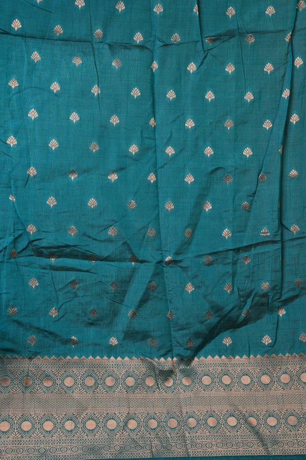 A teal blue-green fabric, likely a Banarasi silk saree body, decorated with small metallic gold zari motifs and featuring a wide gold zari border at the bottom.