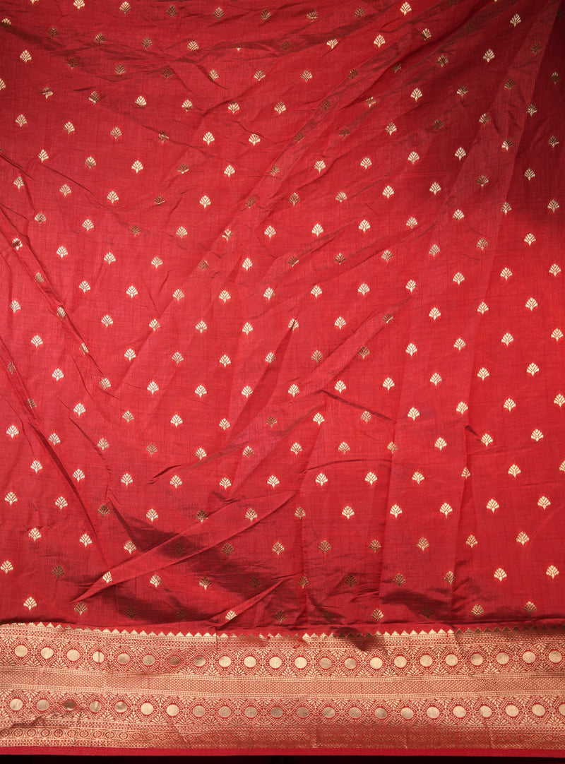A red fabric, likely a saree or dupatta, featuring a repeating pattern of small gold zari motifs and a decorative gold border along the bottom edge.