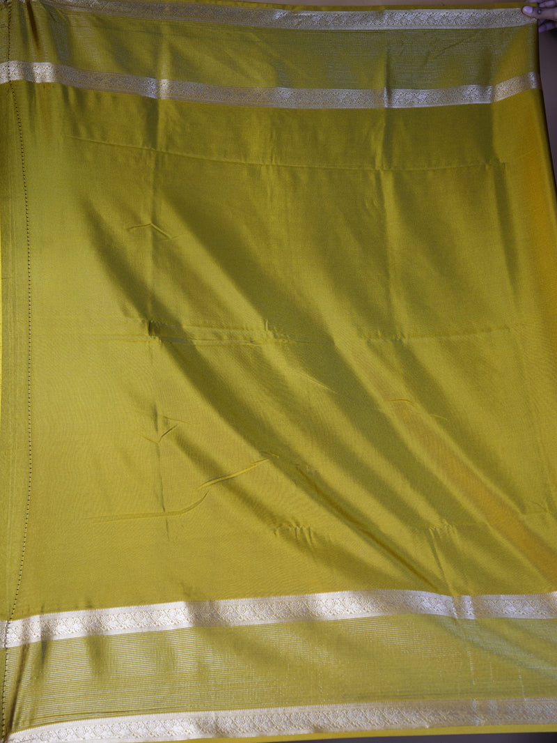 A lime green silk saree with silver zari borders, shown flat with visible folds and texture.