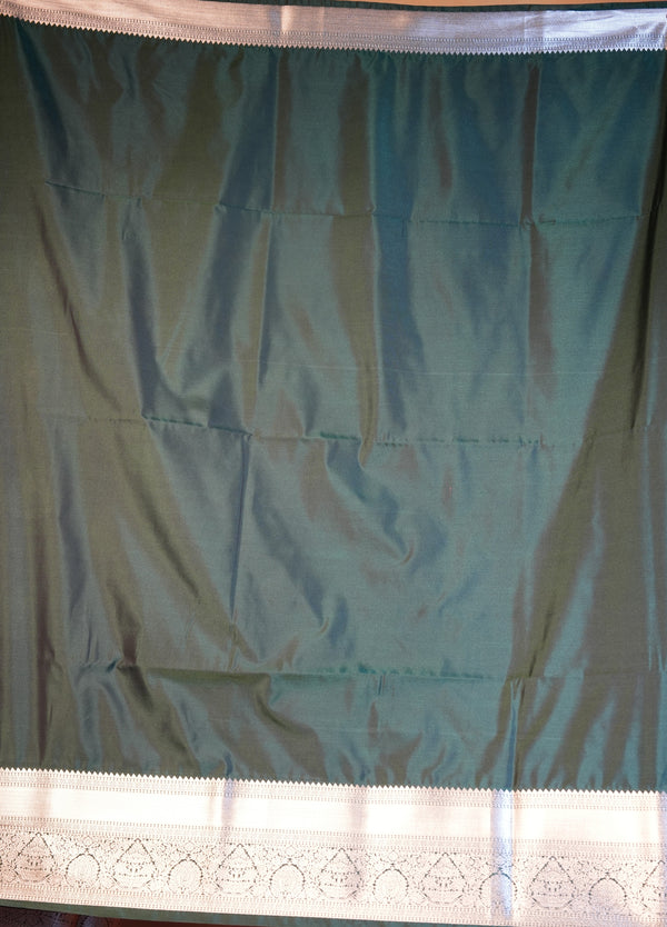 A dark teal-green fabric panel with a white border featuring intricate embroidered patterns.