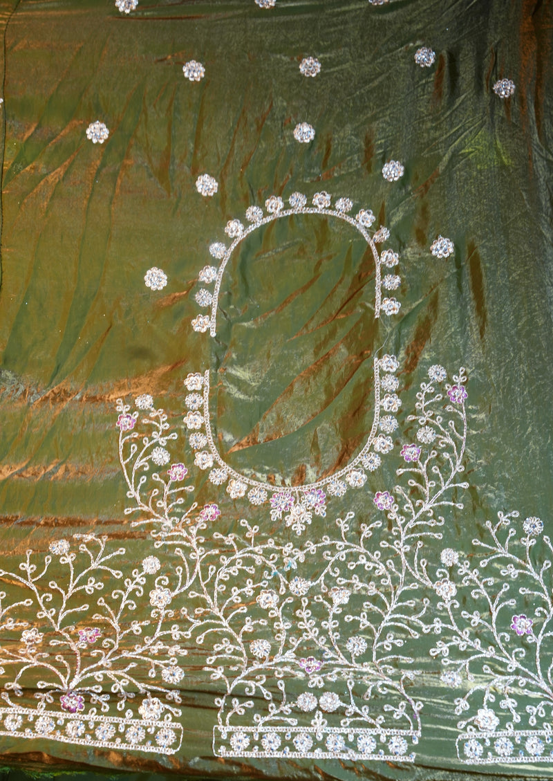A close-up of an olive green fabric with white and light purple floral embroidery, featuring a central oval neckline design.