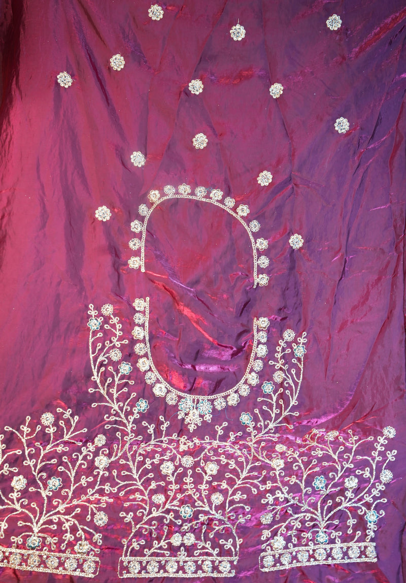 A close-up of a magenta-purple fabric, likely a traditional ethnic garment, featuring intricate silver and white floral embroidery and beadwork.