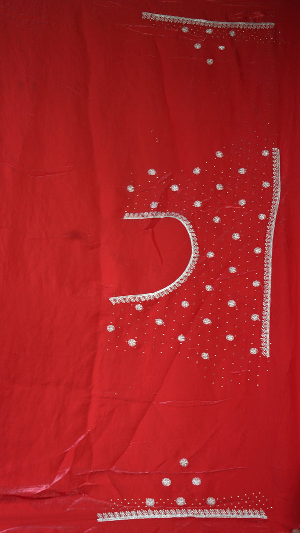 A red fabric garment, likely a salwar suit kameez or kurta, featuring white embroidered details and small silver mirror work embellishments.