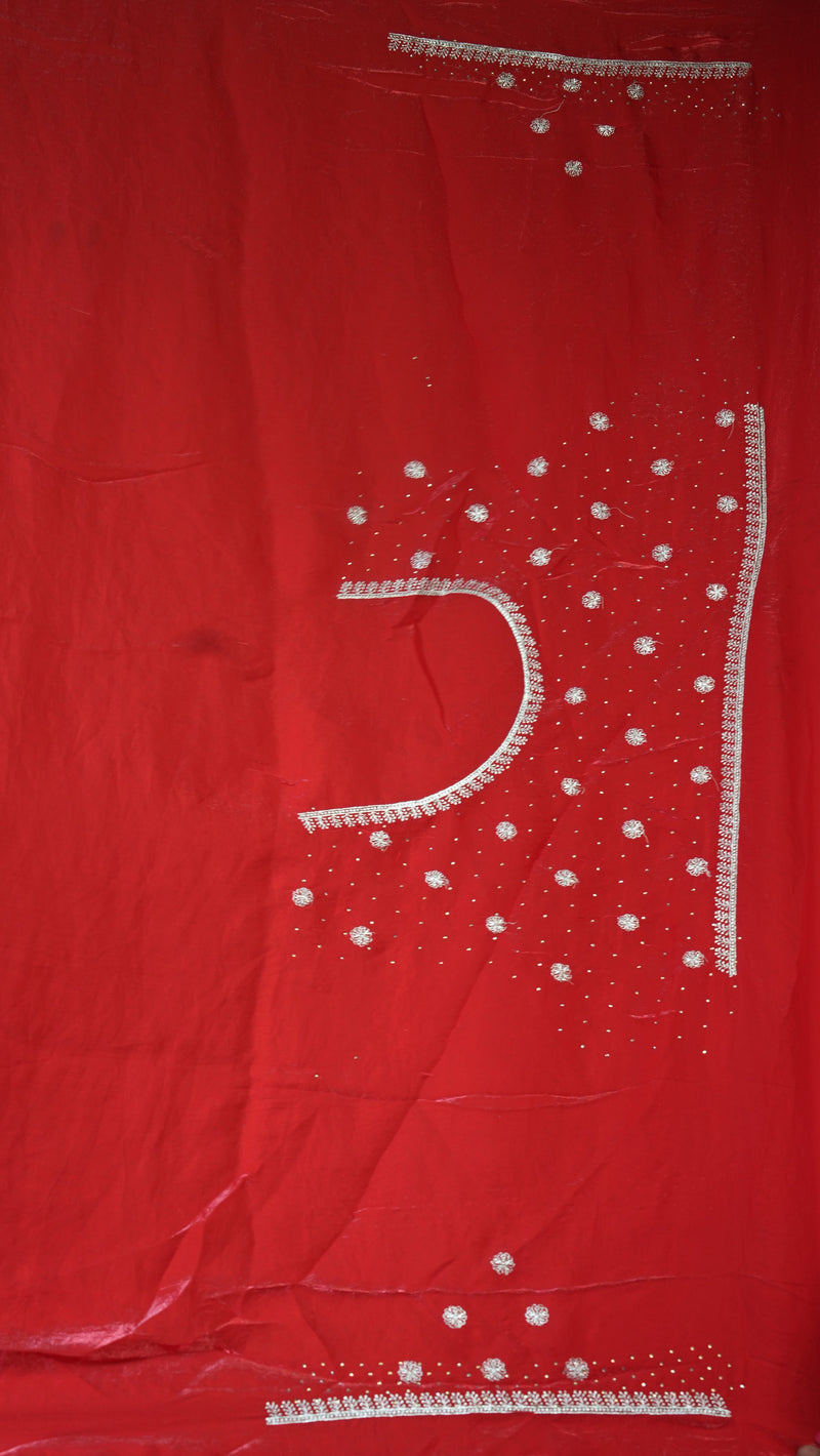 A red fabric garment, likely a salwar suit kameez or kurta, featuring white embroidered details and small silver mirror work embellishments.